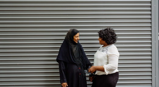 Two women talking in front of a stripy background