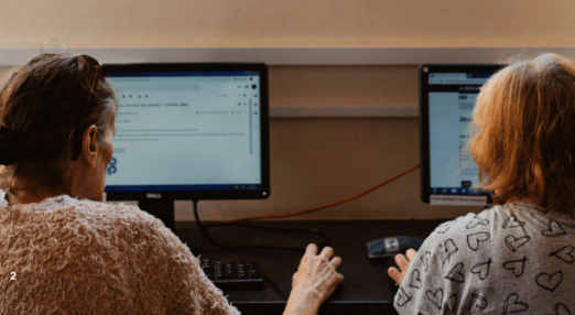 Two people at computers, showing the backs of their heads