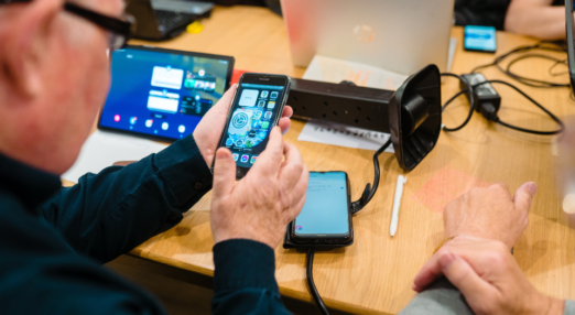 A man holding a phone with other electronic devices in the background