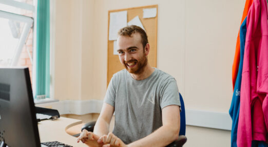 A man smiling using a computer