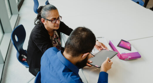 A woman helping a man setup and use a tablet