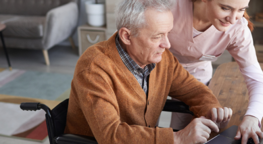 A woman helping a man use a computer